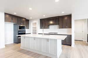 Kitchen with a center island with sink, black oven, stainless steel microwave, and sink