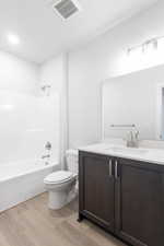 Full bathroom featuring hardwood / wood-style floors, vanity, bathtub / shower combination, and toilet