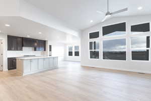 Unfurnished living room with light hardwood / wood-style floors, ceiling fan, lofted ceiling, and sink