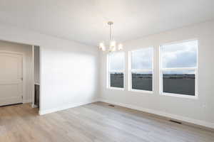 Unfurnished room featuring a chandelier and light wood-type flooring