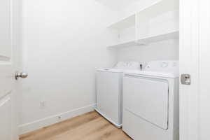 Washroom with separate washer and dryer and light wood-type flooring