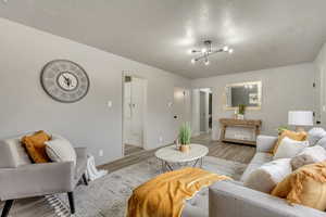 Living room featuring light hardwood / wood-style flooring, a textured ceiling, and an inviting chandelier