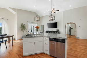 Kitchen featuring ceiling fan, sink, stainless steel dishwasher, lofted ceiling, and white cabinets