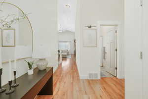 Hall featuring lofted ceiling and light wood-type flooring