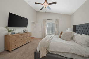 Carpeted bedroom featuring ceiling fan and lofted ceiling