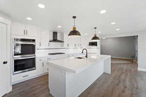 Kitchen with double wall ovens, sink in island, pendant and recessed lighting