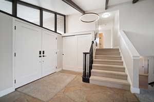 Entrance foyer featuring beamed vaulted ceiling, stone entry floor, and windows accommodating natural light