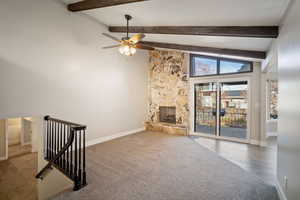 Living room with new carpeting, vaulted ceiling with beams, a stone fireplace, ceiling fan and access to multi-level patio