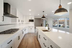 Kitchen featuring gas cooktop and wall hood vent, laminate flooring, ORB finishes, arched kitchen faucet