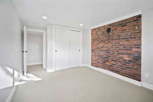 Bedroom with carpet, brick wall feature, and a closet