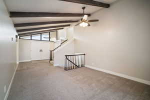 Entry/Living Room featuring vaulted ceiling with beams, ceiling fan, new carpeting, natural stone entry and windows exposing natural light