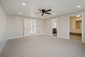 Primary bedroom with primary bathroom, ceiling fan, new carpeting and primary walk-in closet