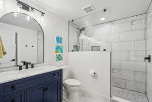 Bathroom featuring toilet, vanity, a textured ceiling, and tiled shower