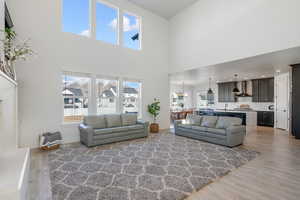 Living room with sink, a chandelier, a high ceiling, and hardwood / wood-style flooring