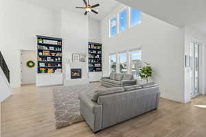 Living room featuring ceiling fan, light wood-type flooring, and a high ceiling