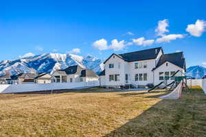 Rear view of property featuring a mountain view, a playground, and a yard