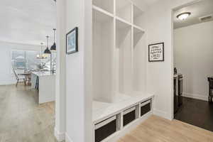 Mudroom featuring a notable chandelier, wood-type flooring, and a textured ceiling