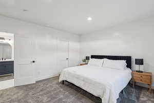 Bedroom featuring ensuite bathroom and dark carpet