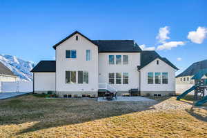 Back of house featuring a lawn, a patio area, and a mountain view