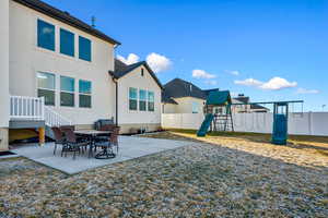 Rear view of property featuring a playground and a patio area