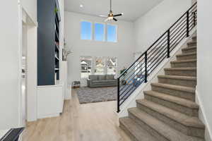 Foyer entrance featuring ceiling fan, light hardwood / wood-style flooring, and a high ceiling