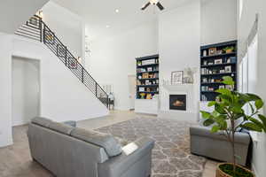 Living room with ceiling fan, light wood-type flooring, and a high ceiling