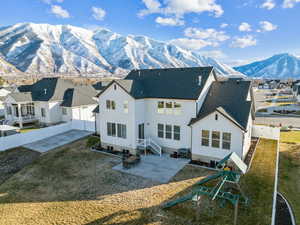 Back of house featuring a mountain view, a patio area, a playground, and a yard