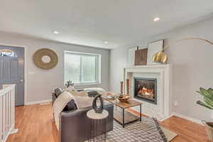 Living room with light wood-type flooring and a tiled fireplace