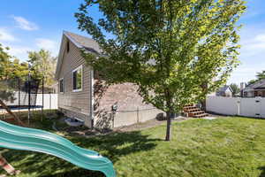 View of home's exterior featuring a playground, a yard, and a trampoline