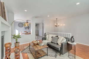 Living room featuring a fireplace, ceiling fan with notable chandelier, and light wood-type flooring