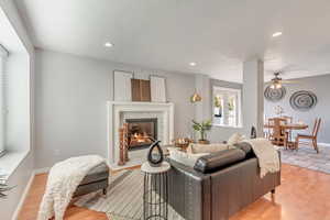 Living room with a fireplace, light hardwood / wood-style floors, and ceiling fan