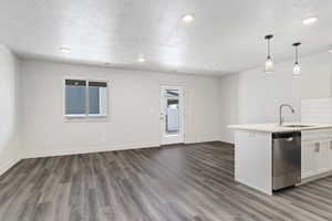 Kitchen with stainless steel dishwasher, a textured ceiling, sink, white cabinets, and hanging light fixtures