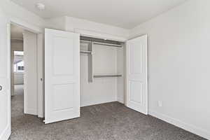 Unfurnished bedroom with dark carpet and a closet