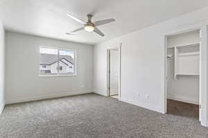 Unfurnished bedroom featuring ceiling fan, a spacious closet, a textured ceiling, carpet floors, and a closet