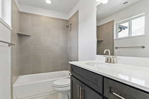 Full bathroom with vanity, toilet, and tiled shower / bath