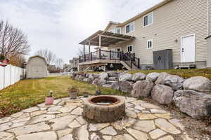 Rear view of house featuring a fire pit, a storage shed, a yard, and a wooden deck