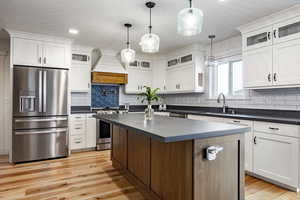 Kitchen with sink, a center island, hanging light fixtures, premium range hood, and appliances with stainless steel finishes