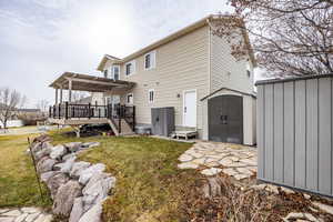 Back of house with a storage unit, a lawn, and a wooden deck