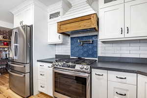 Kitchen featuring white cabinets, decorative backsplash, and appliances with stainless steel finishes