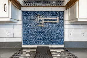 Room details featuring white cabinetry, extractor fan, and stainless steel gas cooktop