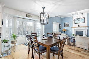 Dining space with wooden walls, a fireplace, light hardwood / wood-style floors, and an inviting chandelier