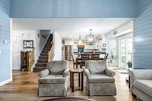 Living room featuring light hardwood / wood-style floors, sink, wooden walls, and an inviting chandelier