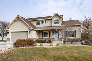 View of front facade with a front lawn, covered porch, and a garage