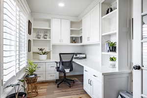 Office with built in desk and light hardwood / wood-style floors