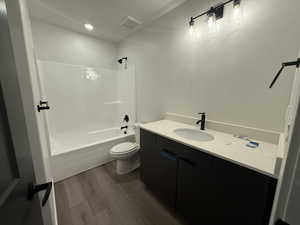 Full bathroom featuring hardwood / wood-style floors, vanity, toilet, and tub / shower combination