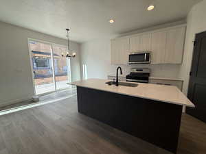 Kitchen featuring sink, an inviting chandelier, an island with sink, decorative light fixtures, and appliances with stainless steel finishes