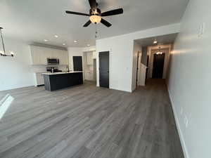 Kitchen with sink, stainless steel appliances, hardwood / wood-style floors, decorative light fixtures, and a kitchen island with sink