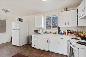 Kitchen featuring white cabinets, white appliances, and sink