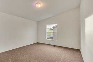 Spare room with carpet and vaulted ceiling