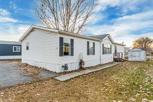 View of side of property featuring a yard and a storage shed